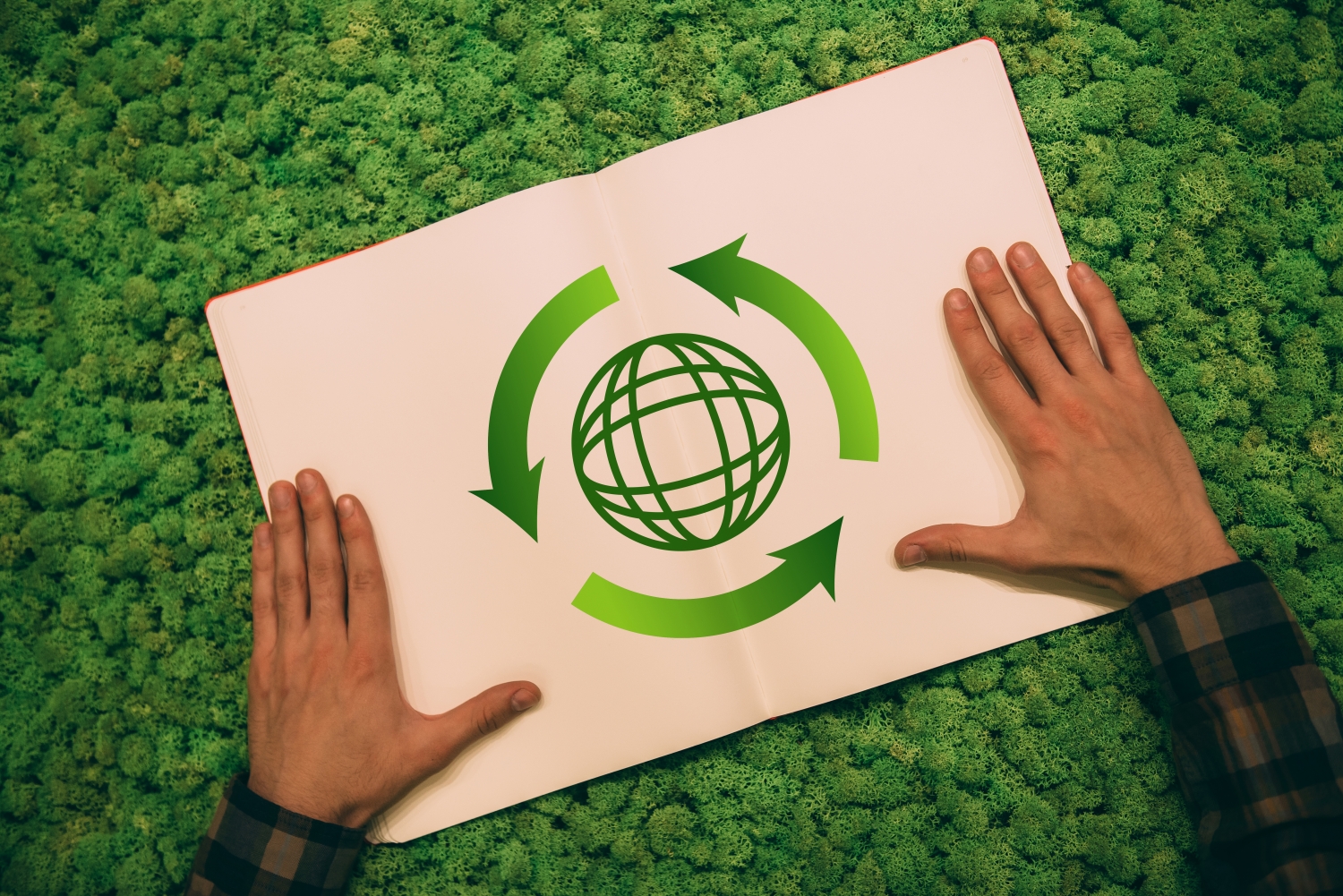 Protect the environment. Top view close-up image of man holding hands on his notebook with arrow and planet symbol at moss background